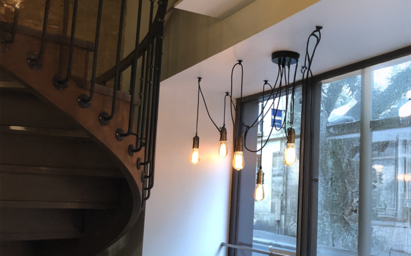Suspension industrielle avec ampoules vintage près d’un escalier en colimaçon en métal