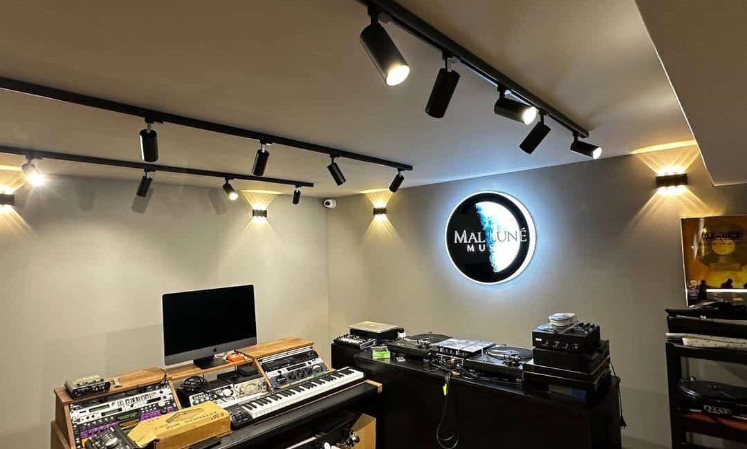 Studio de musique moderne avec synthétiseurs, platines vinyles et éclairage sur rail au plafond